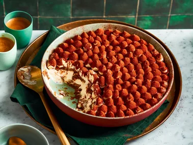 traditional tiramisu recipe with piped meringue topping and cocoa powder on top