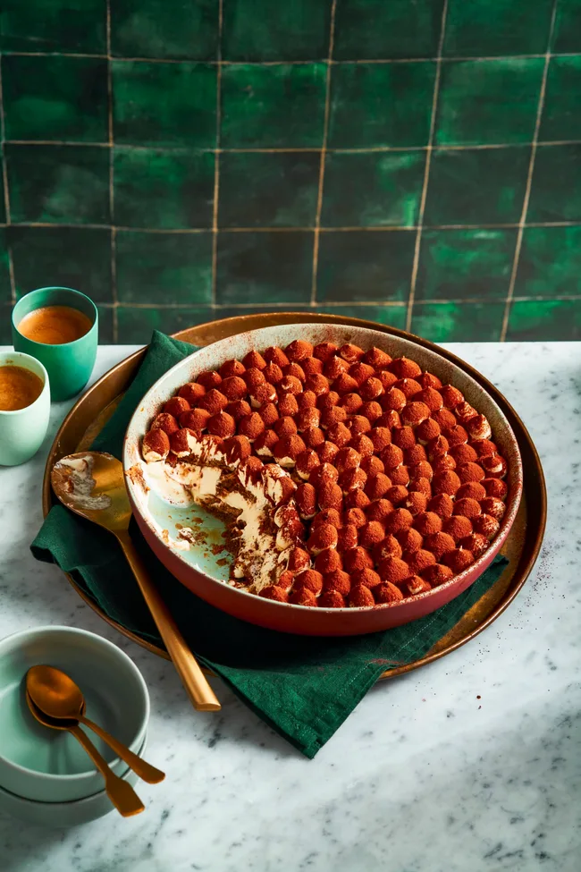 traditional tiramisu recipe with piped meringue topping and cocoa powder on top