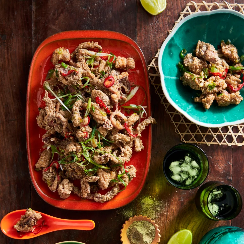 szechuan salt and pepper squid on oval red platter with additional herbs and lemon on the side