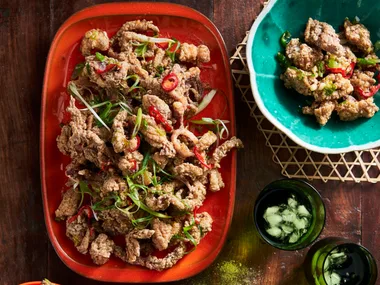 szechuan salt and pepper squid on oval red platter with additional herbs and lemon on the side