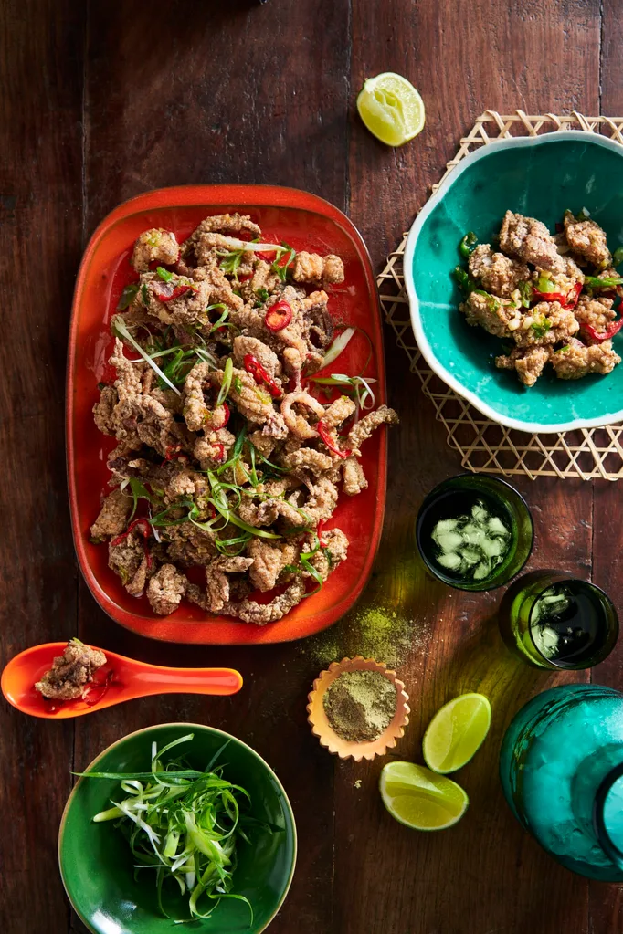 szechuan salt and pepper squid on oval red platter with additional herbs and lemon on the side