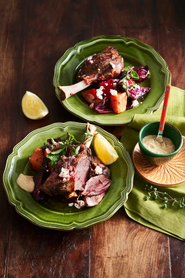 lamb shanks with beetroot and lemon wedges on bright green plate
