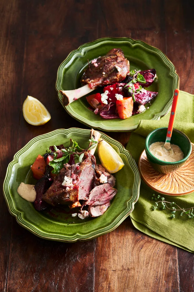lamb shanks with beetroot and lemon wedges on bright green plate