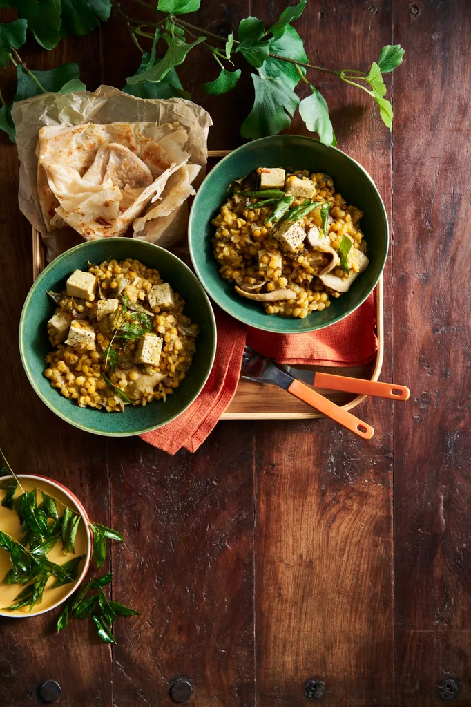 tofu and lentil vegetable stew in two green bowls with naan on the side