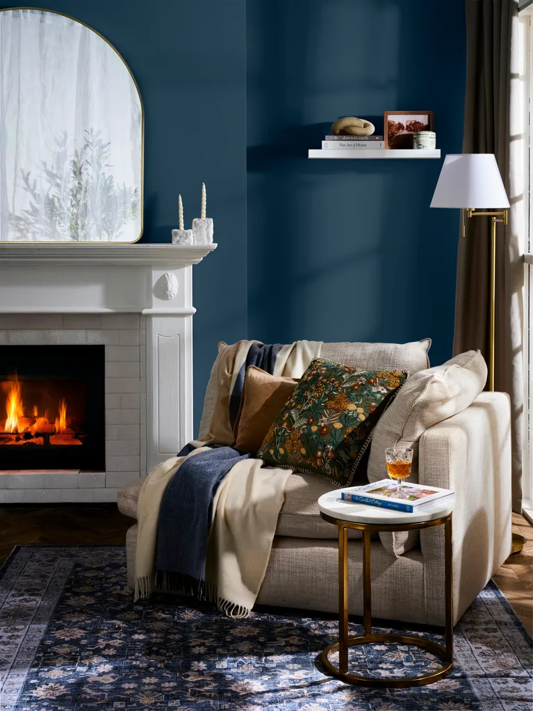 classic cosy nook idea with freedom couch end with blankets draped over it and dark blue walls, fireplace and arched mirror on mantel
