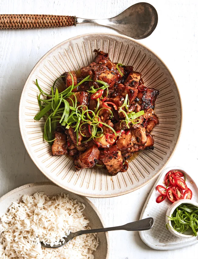 pork belly steamed in red spicy sauce with spring onion sprinkled on top and rice on the side