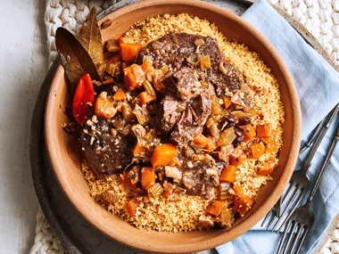 slow cooked beef cheeks with couscous and tomatoes in orange bowl