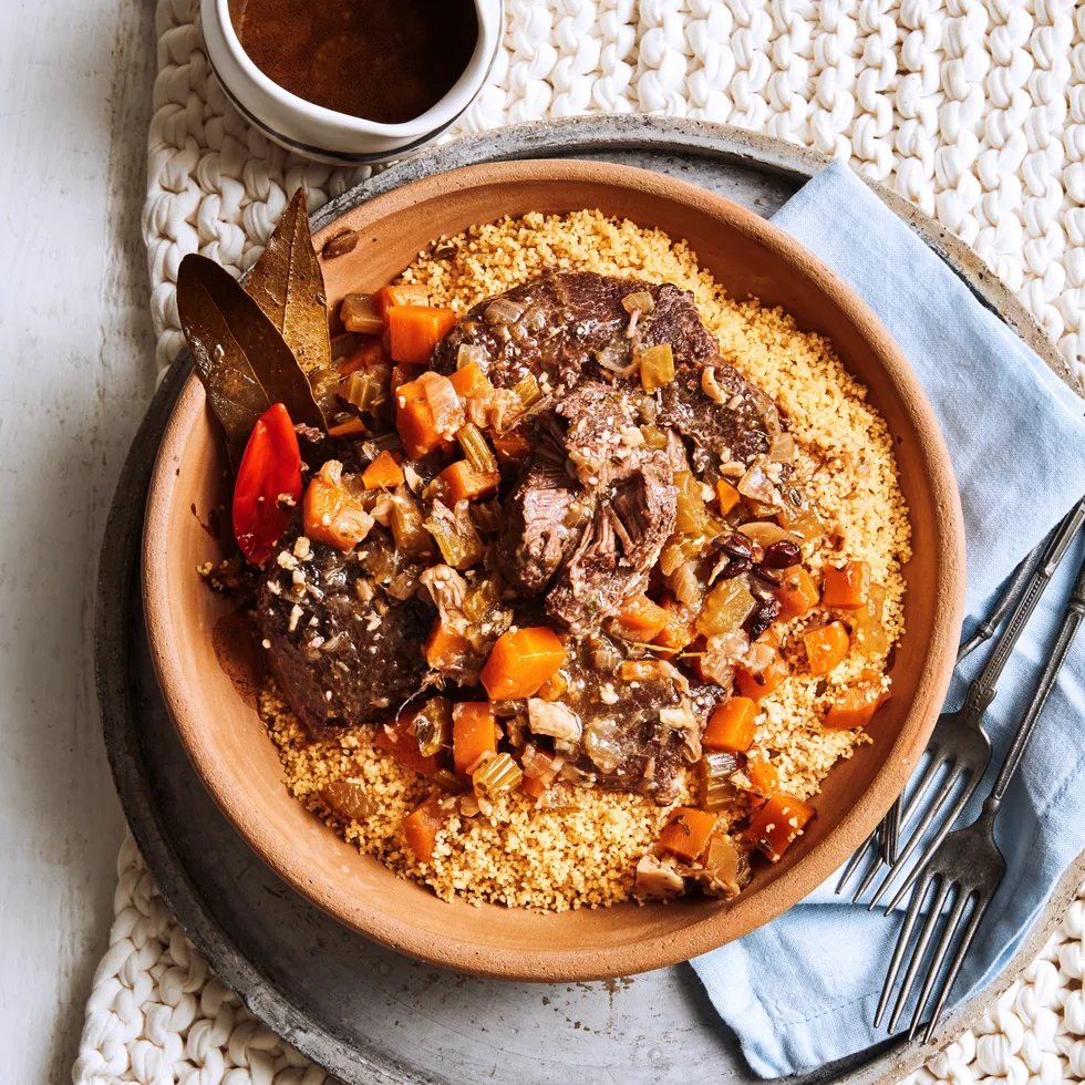 slow cooked beef cheeks with couscous and tomatoes in orange bowl