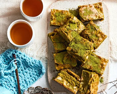 brownies piled on plate with dusting of green matcha on top