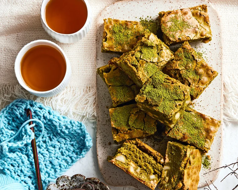brownies piled on plate with dusting of green matcha on top