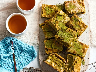 brownies piled on plate with dusting of green matcha on top