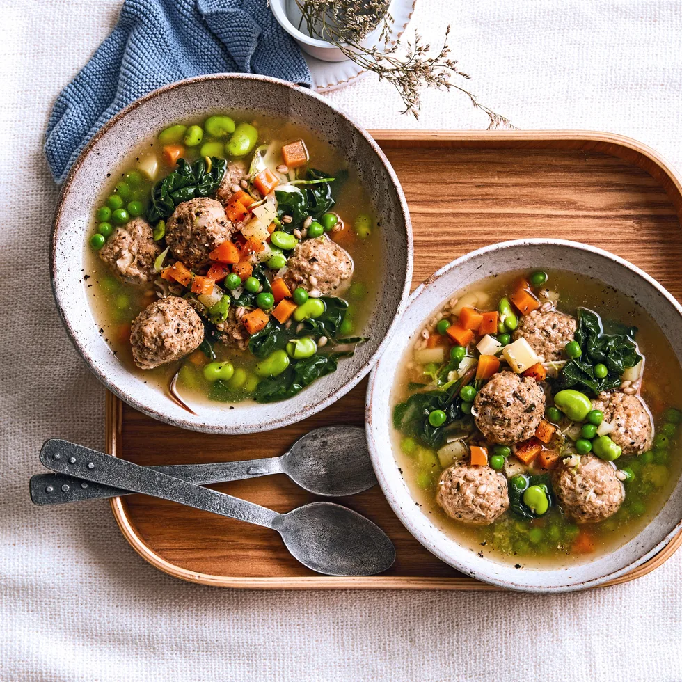 pearl barley stew with chicken dumplings peas and carrots floating in it