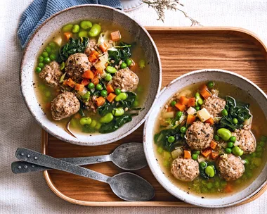 pearl barley stew with chicken dumplings peas and carrots floating in it