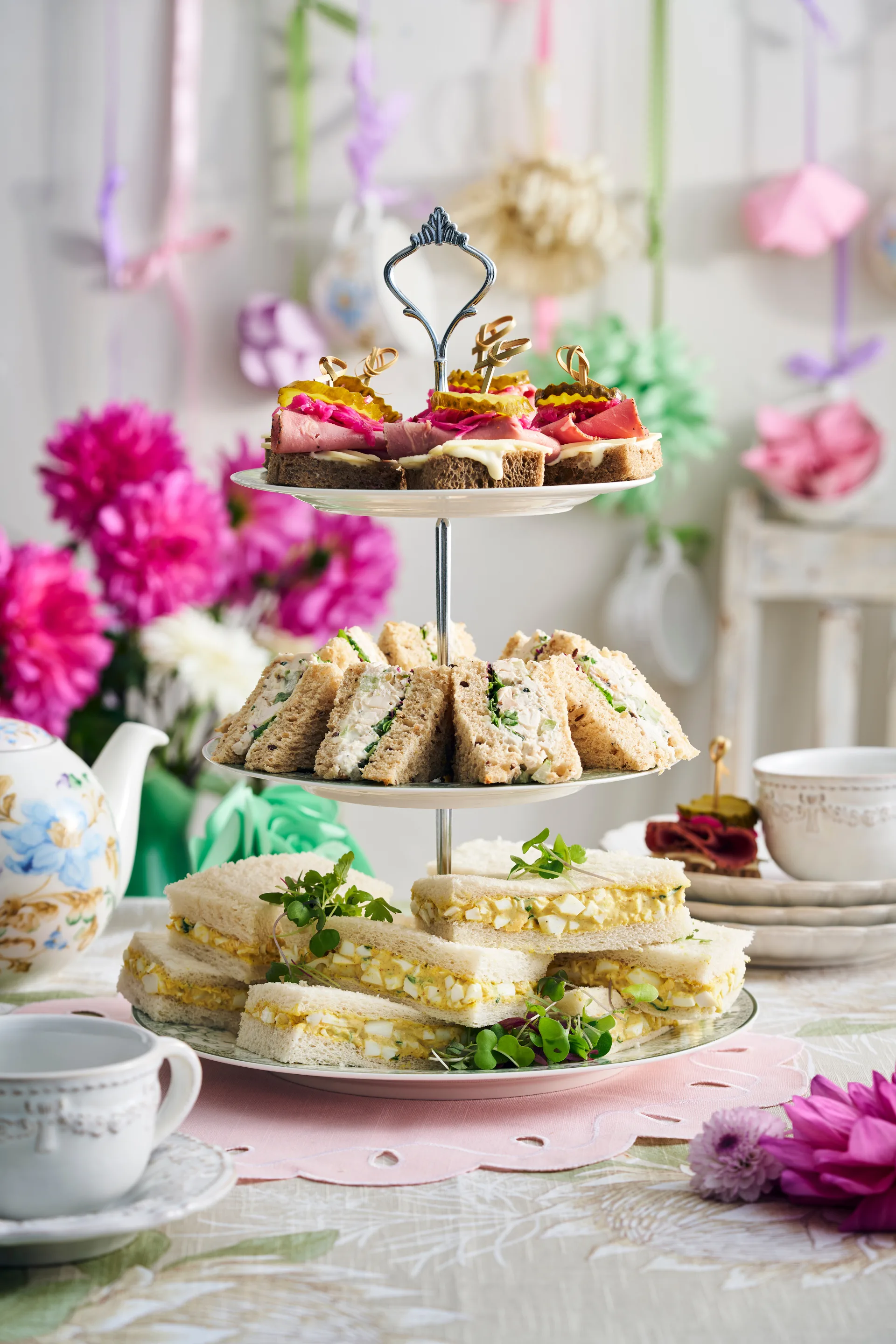 finger sandwiches made three ways on a high tea serving tower and flower decorations