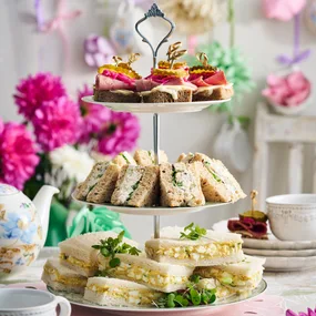 finger sandwiches made three ways on a high tea serving tower and flower decorations