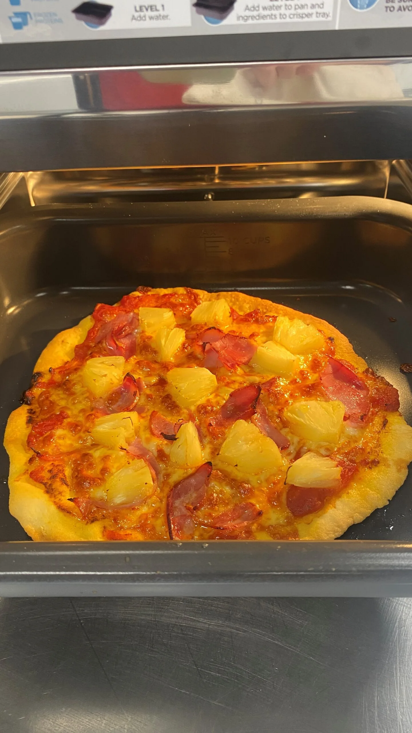 pizza on tray inside multicooker oven close up of pineapple pizza with ham and cheese