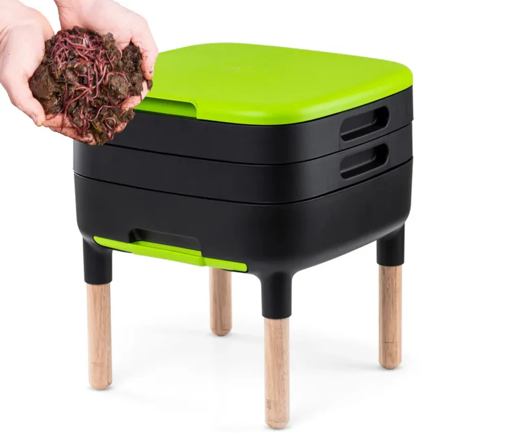 worm farm with green lid and hands on the side holding dirt with worms in it