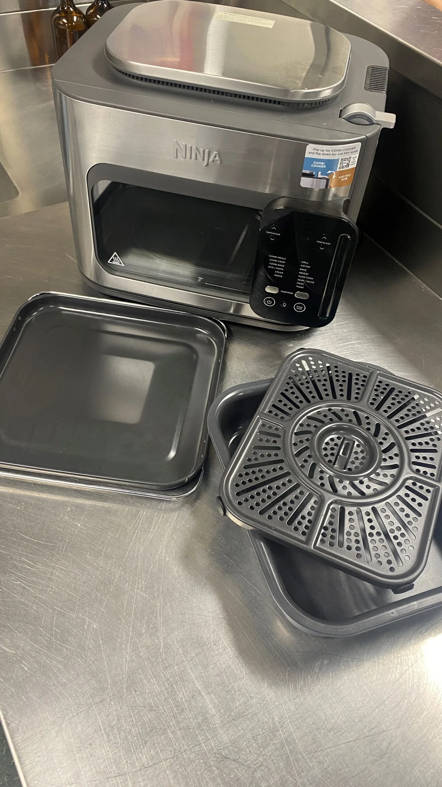mulitcooker accessories laid out in front of machine with baking and roasting trays