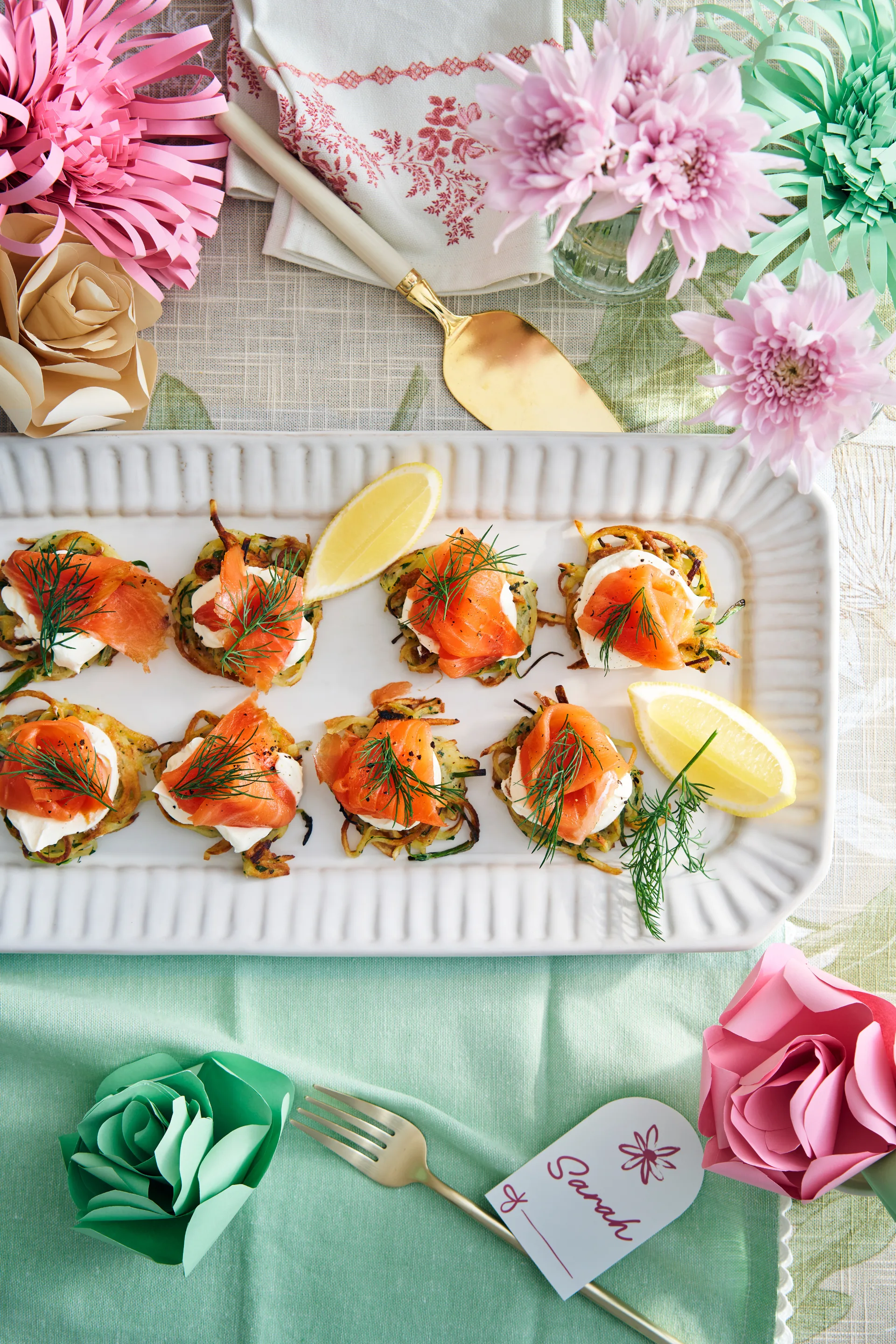 salmon rosti with lemon on white rectangle plate surrounded by paper flowers