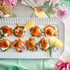 salmon rosti with lemon on white rectangle plate surrounded by paper flowers