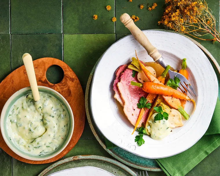 corned beef with carrot in bowl with white sauce drizzled on top