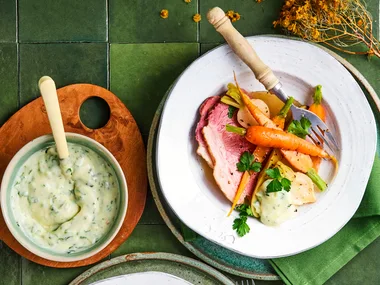 corned beef with carrot in bowl with white sauce drizzled on top