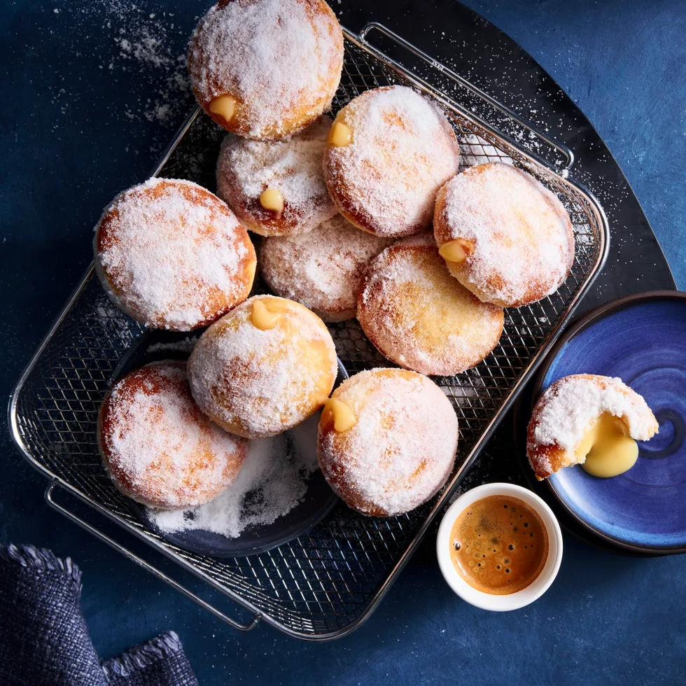 air fryer doughnuts with lemon curd filling in them on a black tray on blue tablecloth