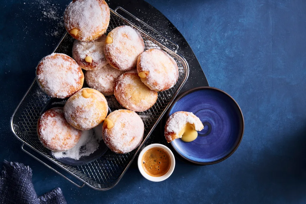 air fryer doughnuts with lemon curd filling in them on a black tray on blue tablecloth
