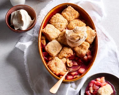 pear and berry cobbler with scones cooked on top in oval tray with spoon sticking out