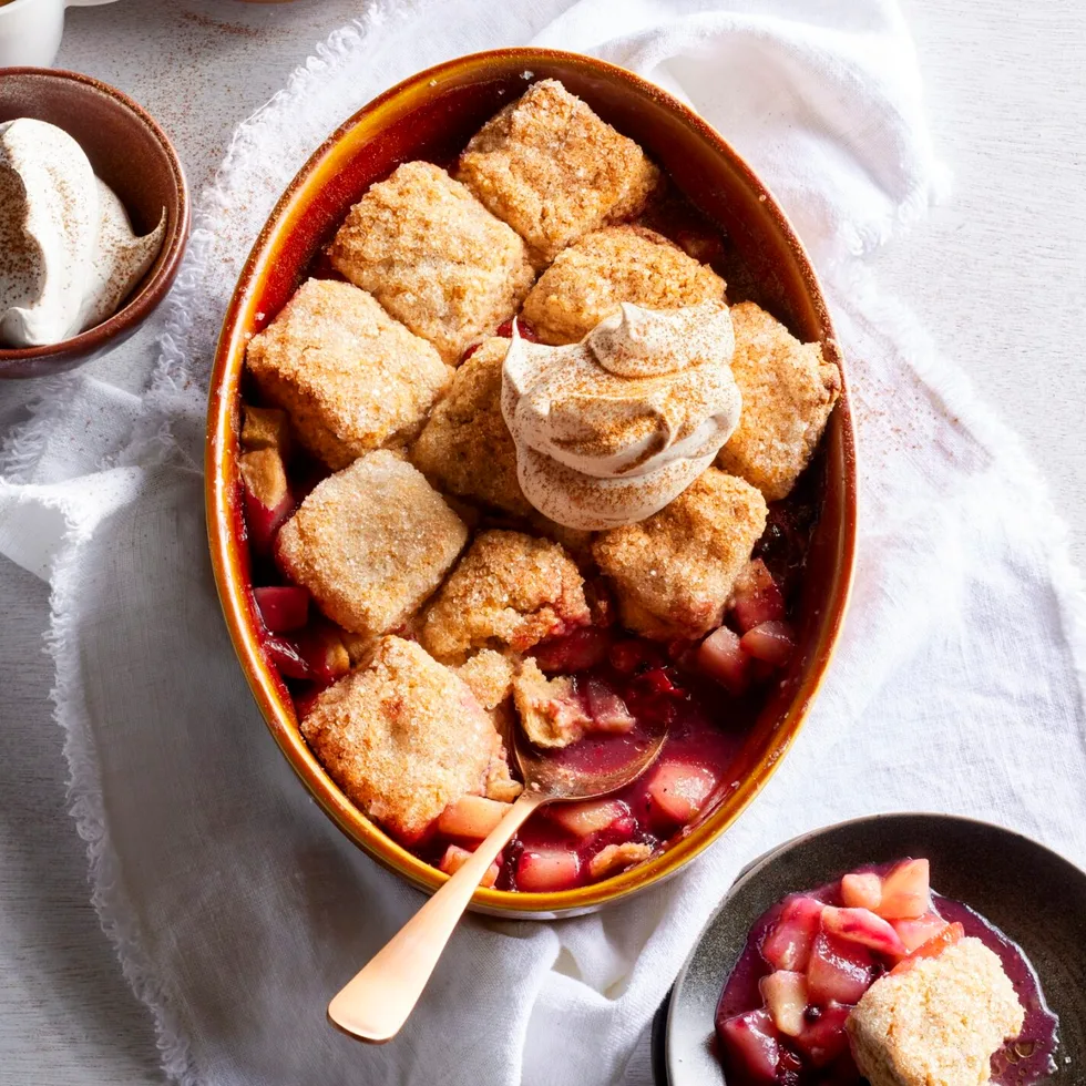 pear and berry cobbler with scones cooked on top in oval tray with spoon sticking out