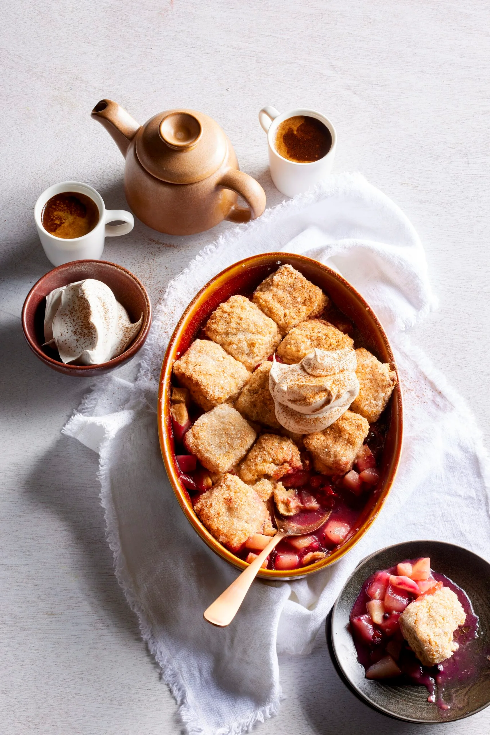 pear and berry cobbler with scones cooked on top in oval tray with spoon sticking out