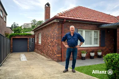 scotty cam standing outside standard brick aussie home with chimney and driveway. scott cam going though his home maintenance checklist