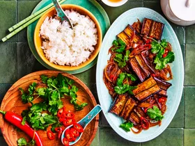 eggplant stir fry strips of eggplant in oval blue dish with rice and vegies on the side