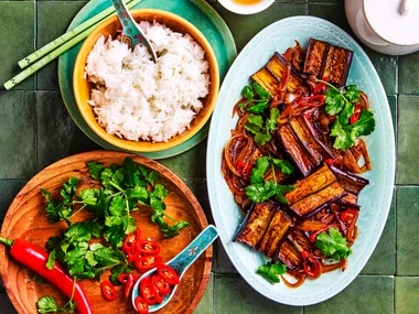 eggplant stir fry strips of eggplant in oval blue dish with rice and vegies on the side