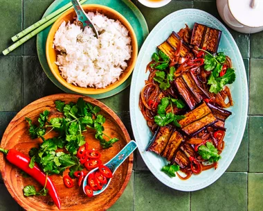 eggplant stir fry strips of eggplant in oval blue dish with rice and vegies on the side