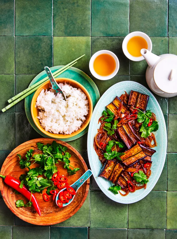 eggplant stir fry strips of eggplant in oval blue dish with rice and vegies on the side