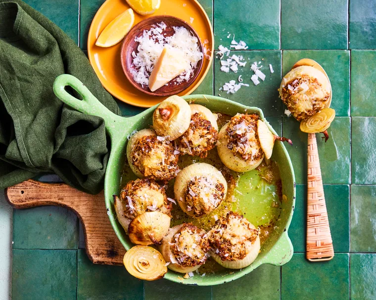 stuffed onions in fry pan that's green and parmesan sprinkled on top