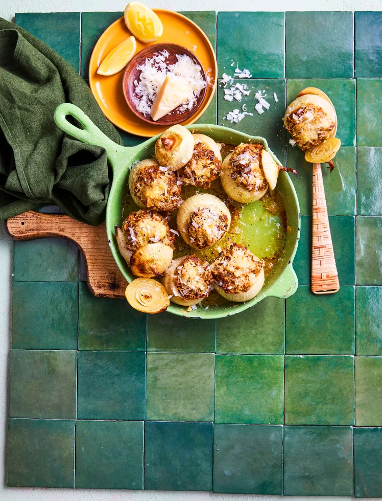 stuffed onions in fry pan that's green and parmesan sprinkled on top