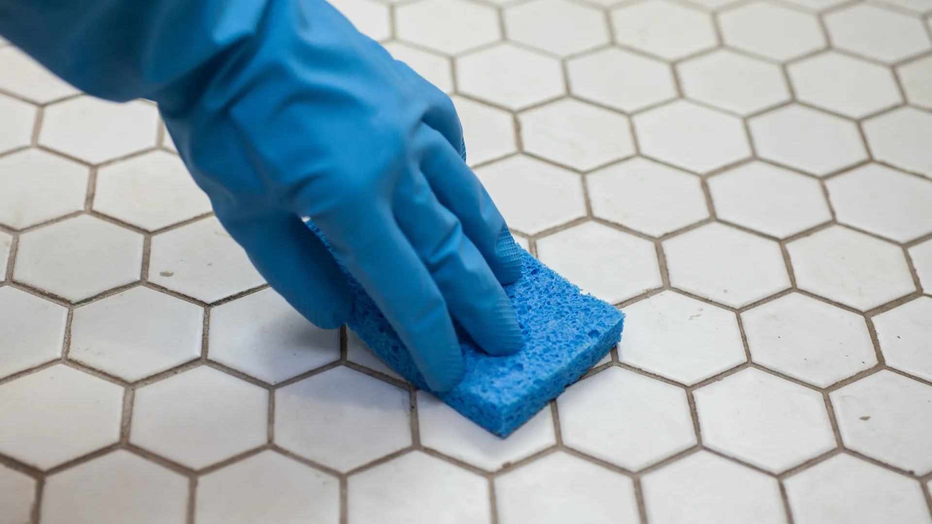 Gruagem de ladrilhos de limpeza com esponja azul