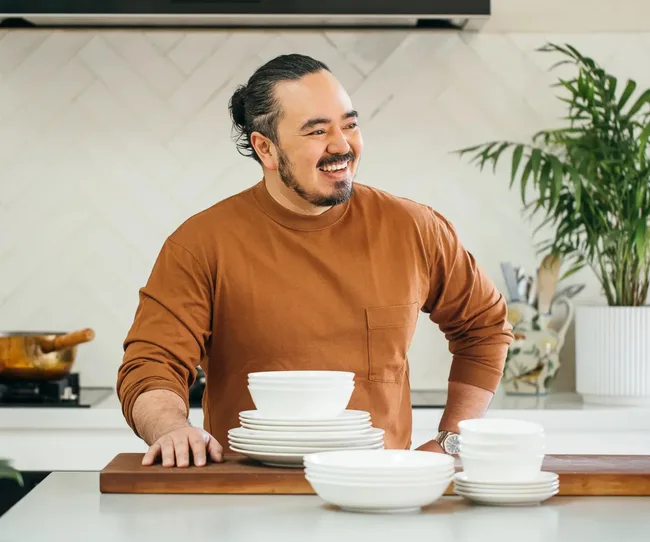 adam liaw in orange jumper with celebrity food brand of white dinnerware