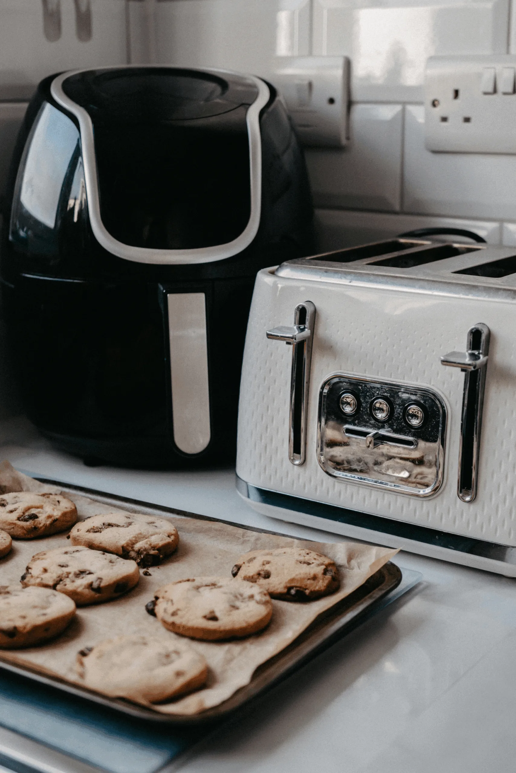 airfryer in kitchen next to a toaster nd a bkaing tray of cookies
