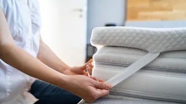 Person putting mattress topper on a mattress