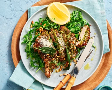 pork cutlets on round plate with lemon wedges and green salad underneath