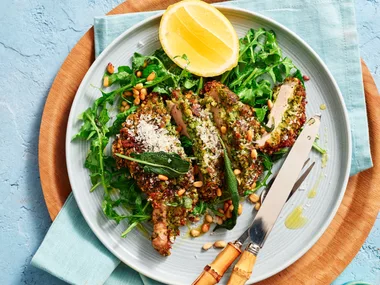 pork cutlets on round plate with lemon wedges and green salad underneath