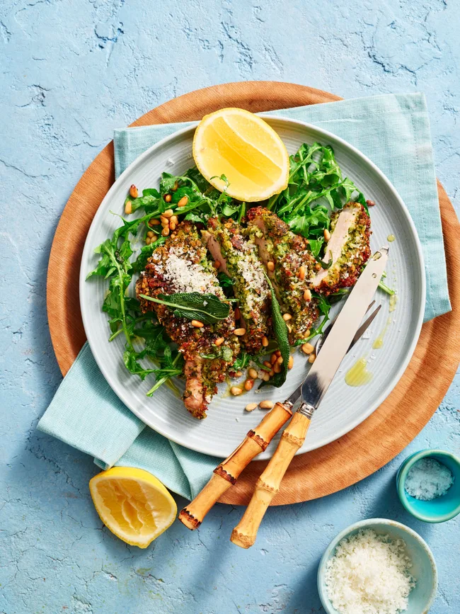 pork cutlets on round plate with lemon wedges and green salad underneath