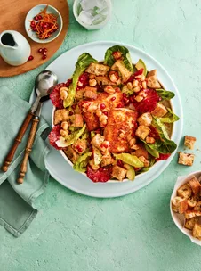 orange and haloumi salad in white bowl with pomegranate seeds and cos lettuce