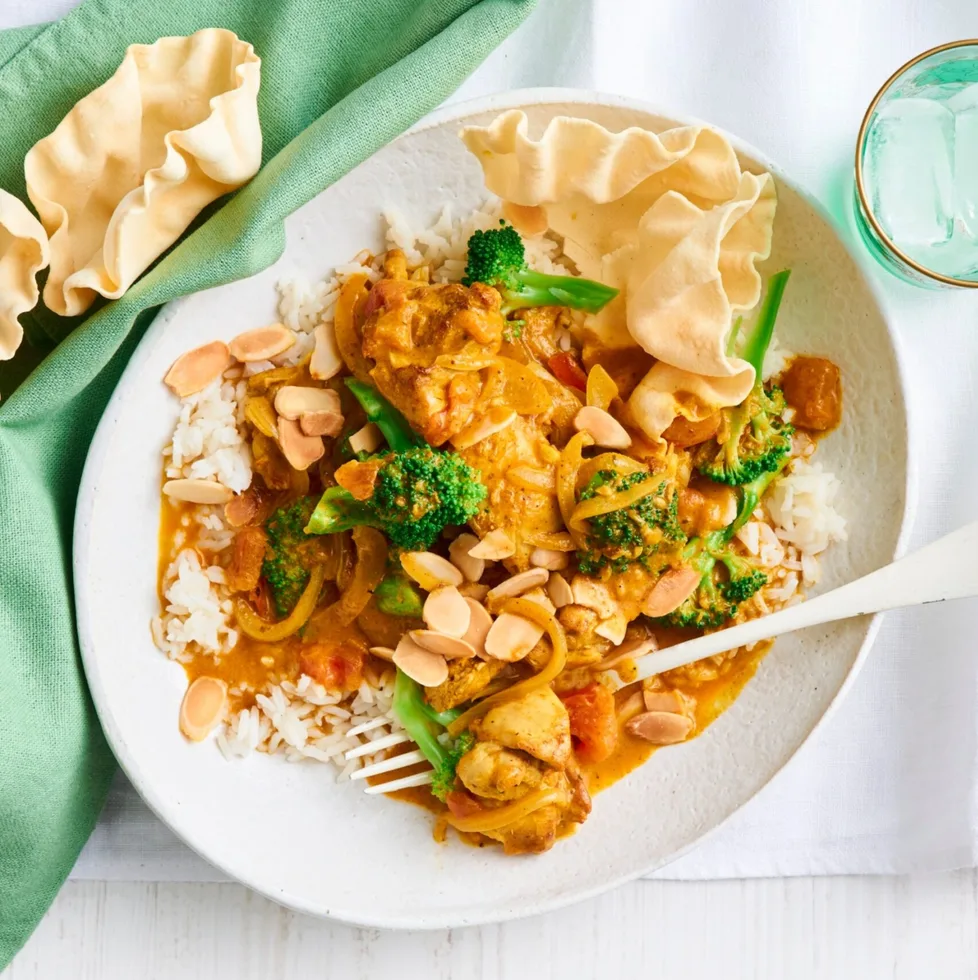 chicken and broccoli orange korma curry with white fork and bowl