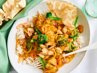 chicken and broccoli orange korma curry with white fork and bowl