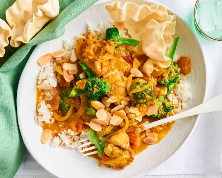chicken and broccoli orange korma curry with white fork and bowl
