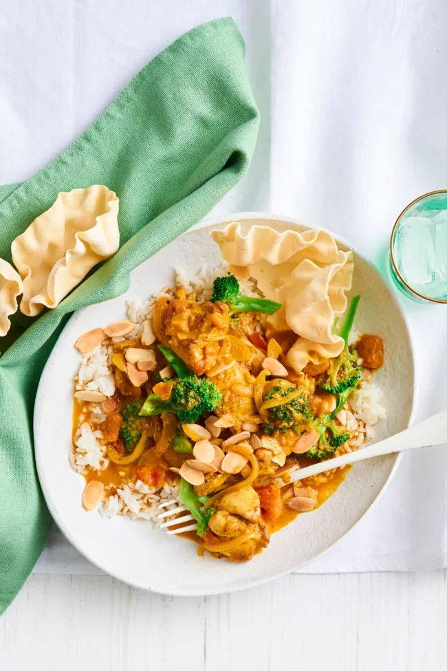 chicken and broccoli orange korma curry with white fork and bowl